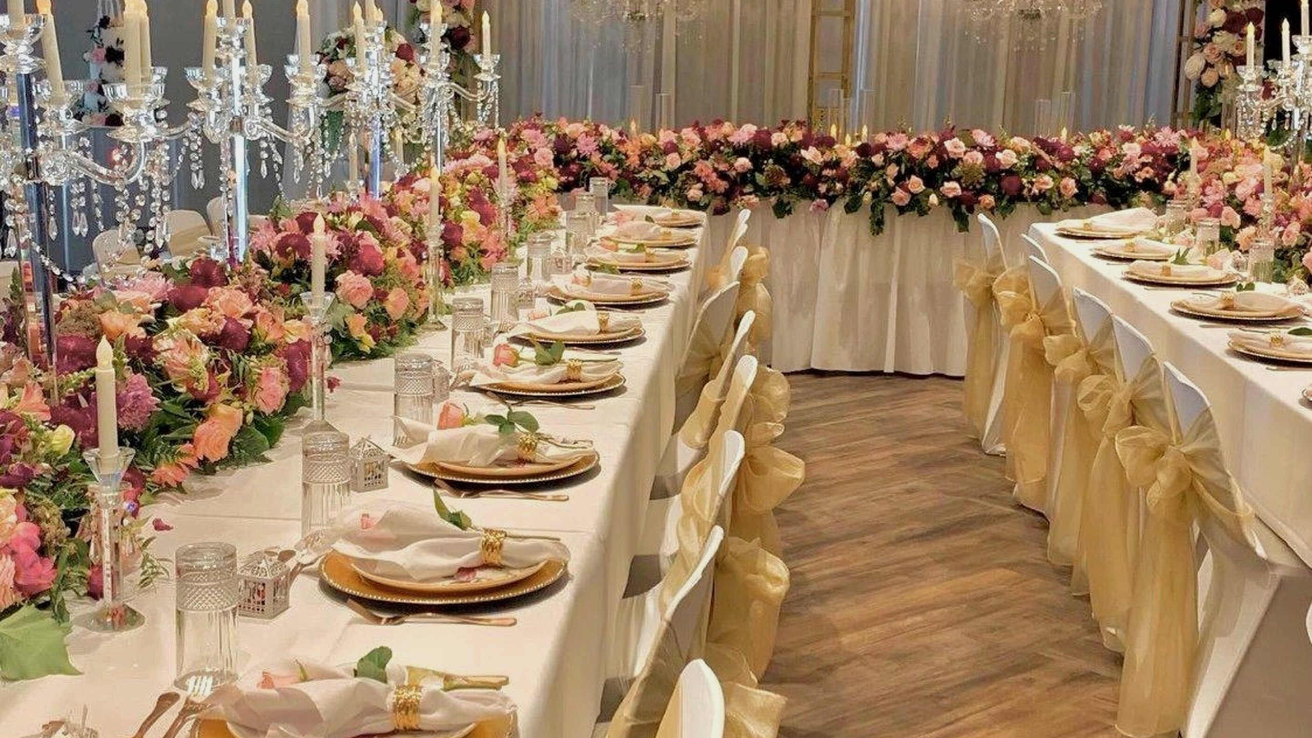 Long reception tables styled with layered pink florals and candlelight
