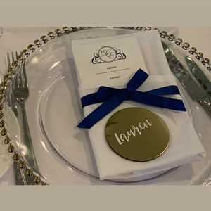 White serviette folded with navy ribbon and place card