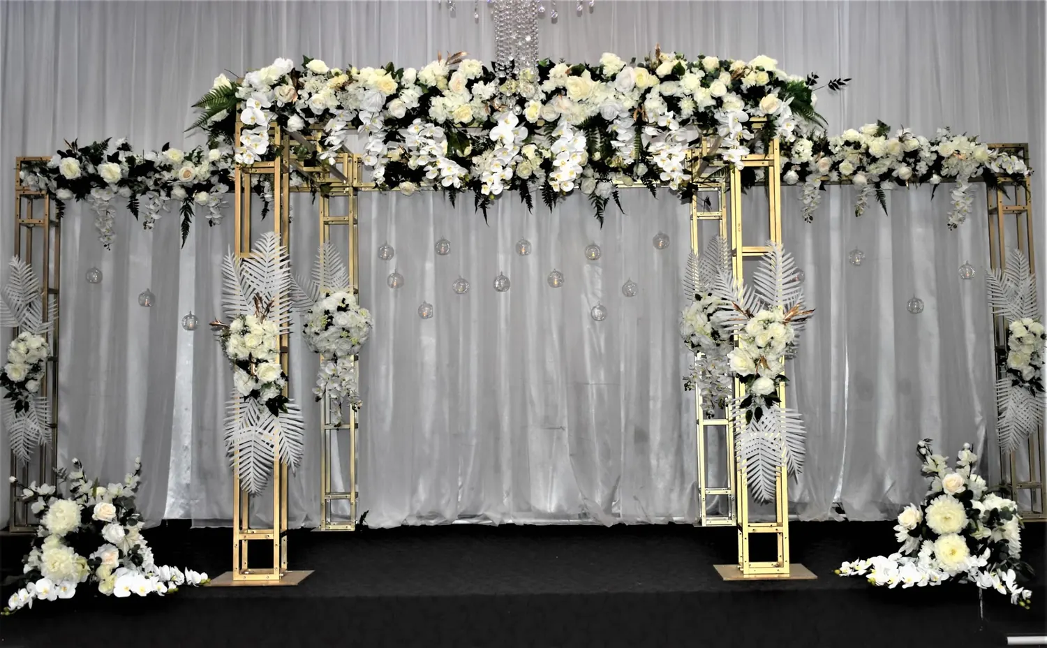 Gold wedding canopy with white florals and draped backdrop